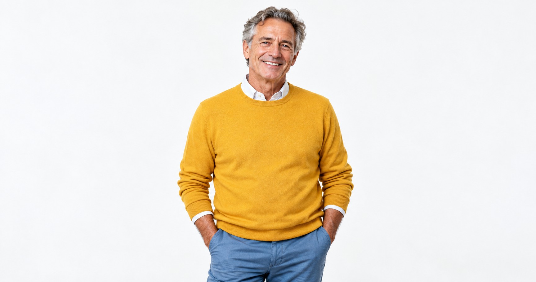 A smiling man in his early sixties in a marigold sweater against a white background.