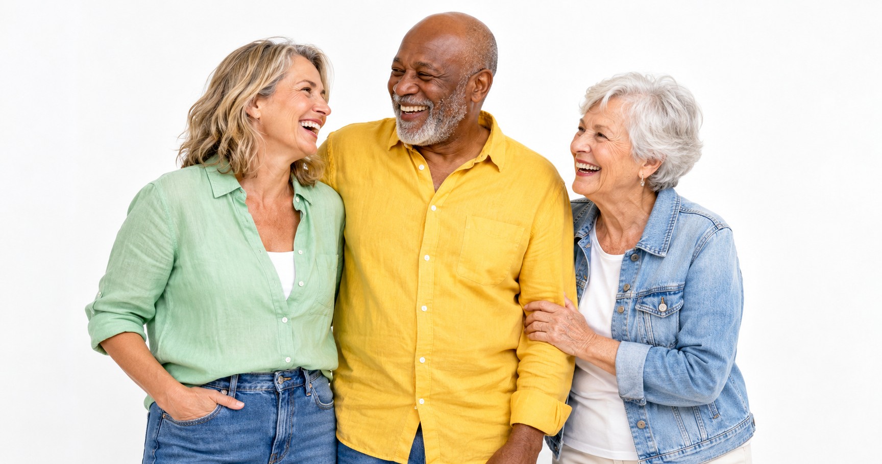 Three friends in their fifties, sixties and seventies laughing together against a white background.